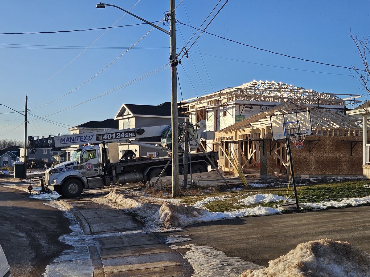 Wood-framed residential structure under construction with roof trusses installed.